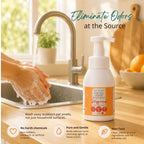 Clean Earth Tangerine Natural Liquid Hand Soap pump bottle on a wooden kitchen counter next to hands washing at a sink, with text reading "Eliminate Odors at the Source" and highlighting non-toxic, gentle ingredients.